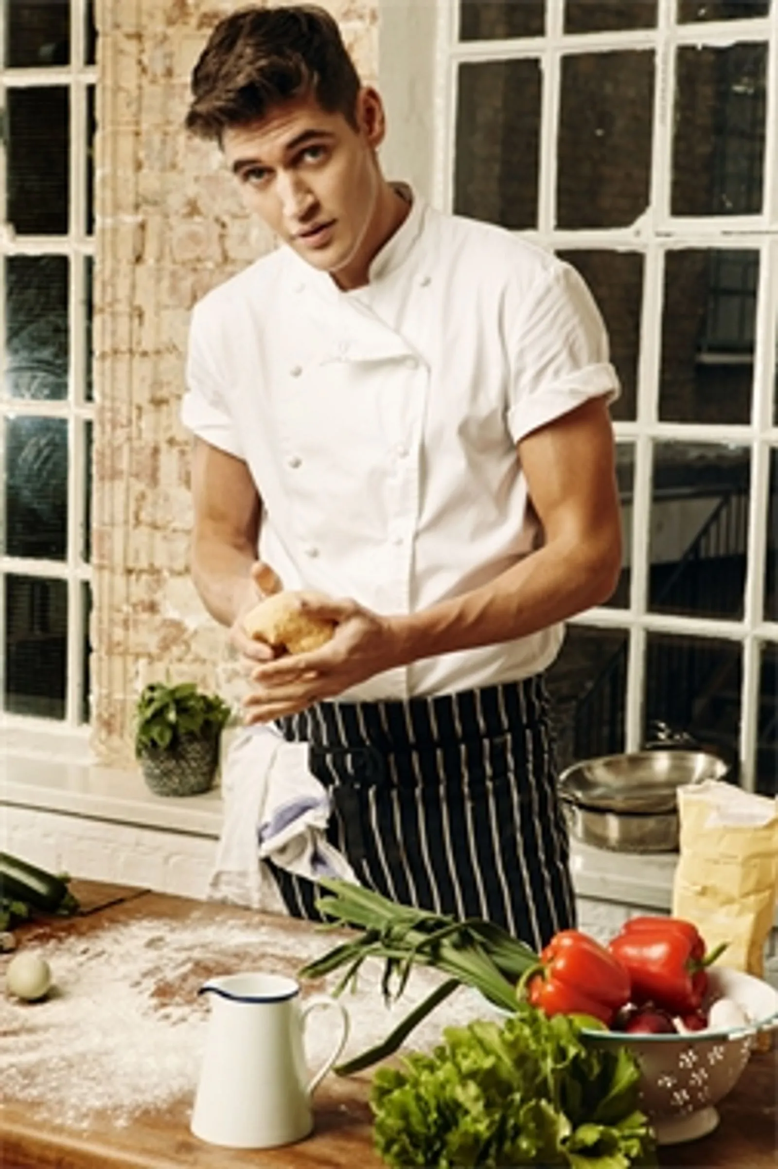Isaac Carew, chef whites and apron, working at a kitchen counter.